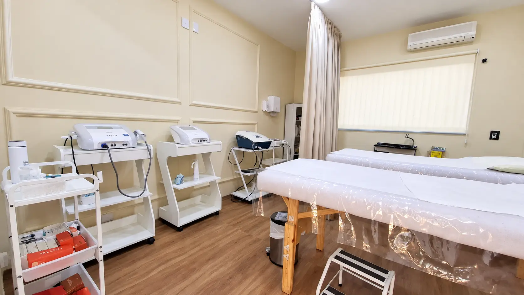 Sala de procedimentos com duas macas, escadinha de apoio e equipamentos de eletroterapia