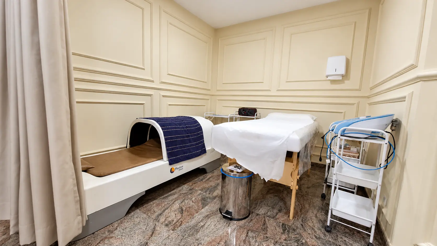 Espaço de termoterapia com cápsula térmica, maca de atendimento e carrinho auxiliar