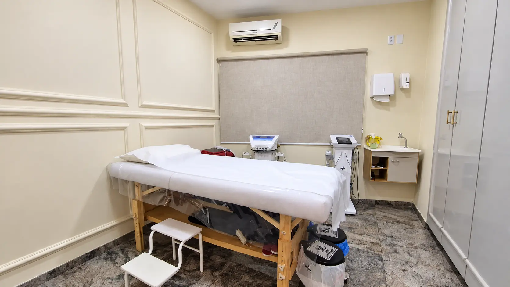 Sala de procedimentos com maca, bancada com pia e armário planejado
